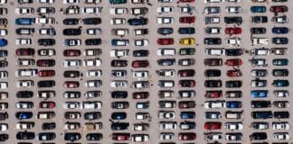 Śnieg z dachu auta – dlaczego jego nieusunięcie jest groźne i nielegalne? Ujęcie lotnicze z góry na duży parking wypełniony rzędami samochodów, ukazujące zorganizowaną symetrię.