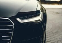 Elegancki, nowoczesny luksusowy samochód z chromowanymi detalami i reflektorami LED na ulicy miejskiej.