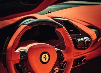 Zbliżenie na luksusowe czerwone wnętrze samochodu sportowego ze stylową kierownicą.